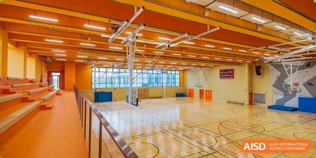 A bright, empty sports hall at Lycée Français de Shanghai is shown with a basketball court and high ceilings.