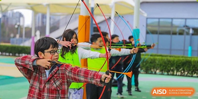 Lycée Français de Shanghai students are participating in an archery class, aiming their bows at targets.