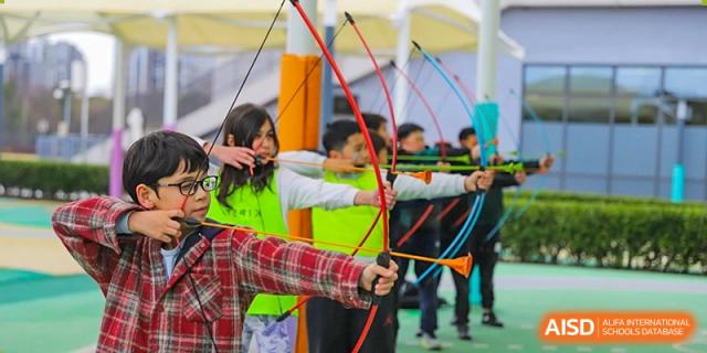 Lycée Français de Shanghai students are participating in an archery class, aiming their bows at targets.