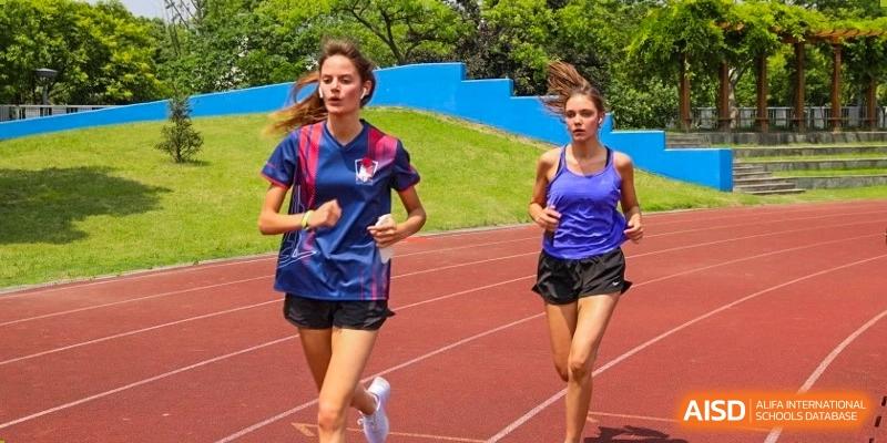 Two female Lycée Français de Shanghai students are running on a track field.