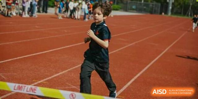 A young Lycée Français de Shanghai student is running on a track field.