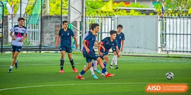 A group of male Lycée Français de Shanghai students is playing soccer on a green field.