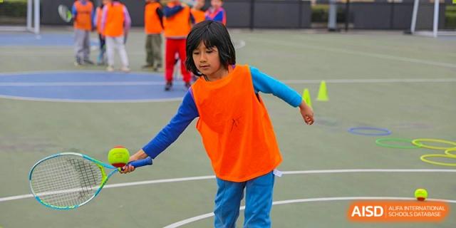 A young Lycée Français de Shanghai student is playing a game while wearing a bright orange vest.