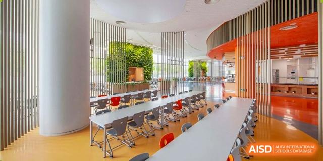 An indoor eating area at Lycée Français de Shanghai is shown with tables and chairs, ready for students to eat.