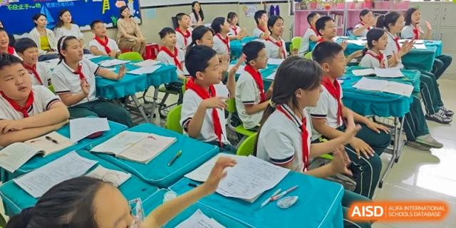 Students seated in a bright classroom, actively participating and looking toward the front of the room at Maple Leaf School- Xiangyang.