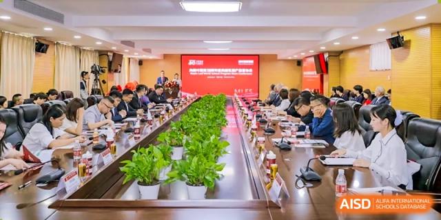 A group of teachers or staff seated around a large conference table in a meeting room, engaged in discussion at Maple Leaf School- Xiangyang.