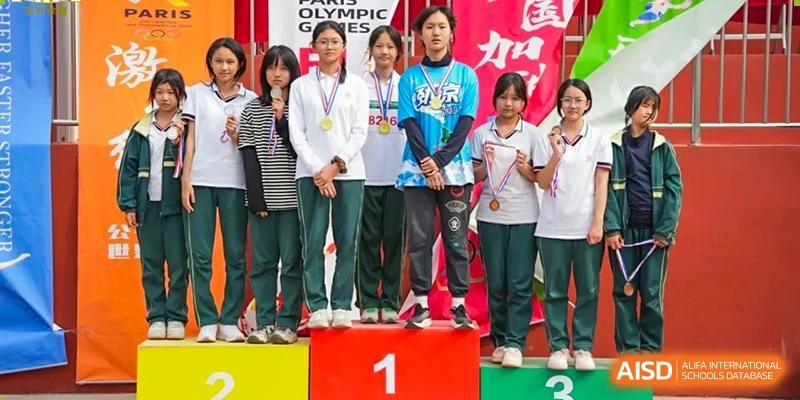 Students from Maple Leaf School - Xiangyang standing on a podium after winning a sports competition, wearing medals.