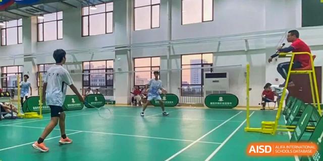 A student from Maple Leaf School - Xiangyang playing badminton in a large, well-lit indoor gymnasium.