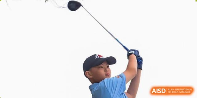A close-up of a student from Maple Leaf School - Xiangyang swinging a golf club, wearing a baseball cap and blue polo shirt.