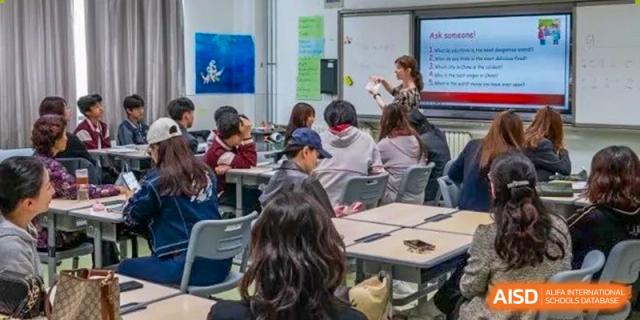 Students sitting in groups around desks engaged in a discussion or collaborative learning activity in a classroom at Weiming International Qingdao.