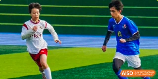 A close-up of a student athlete's legs and feet running on a green turf field during a soccer match at Weiming International Qingdao.