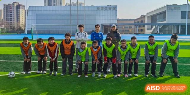 A group of male students, possibly a soccer team, standing side-by-side on the field wearing vests at Weiming International Qingdao.