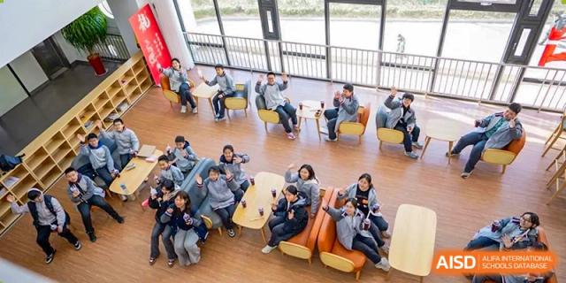 A group of students seated outdoors or near large windows, possibly for an activity or class session at Weiming International Qingdao.