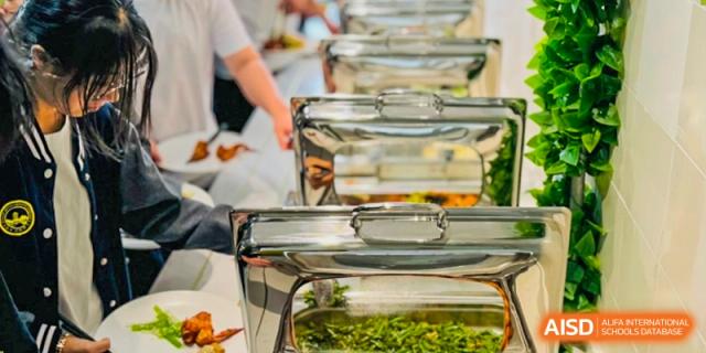 A serving tray containing a side dish or salad, part of a buffet line for students at the dining area of Weiming International Qingdao.