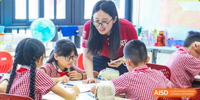 A teacher from Sanya Haiya  Foreign Language School helping a group of young students with a classroom activity.
