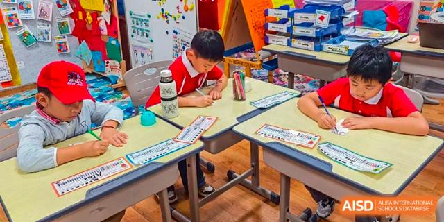 A young student from Sanya Haiya  Foreign Language School focuses on an art project at his desk.