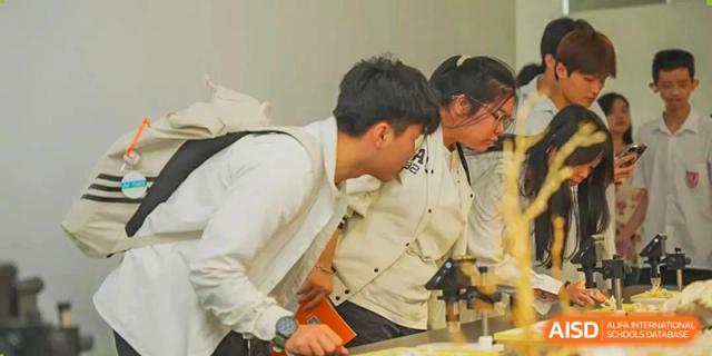 Sanya Haiya  Foreign Language School students examining a specimen under a microscope in a science lab.