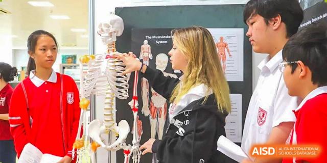A Sanya Haiya  Foreign Language School student pointing to a model of a human skeleton in a science class.
