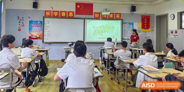 A student from Sanya Haiya  Foreign Language School raising their hand in a classroom.