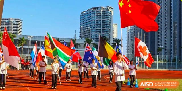 Sanya Haiya Foreign Language School students with flags of different countries at a sports event.