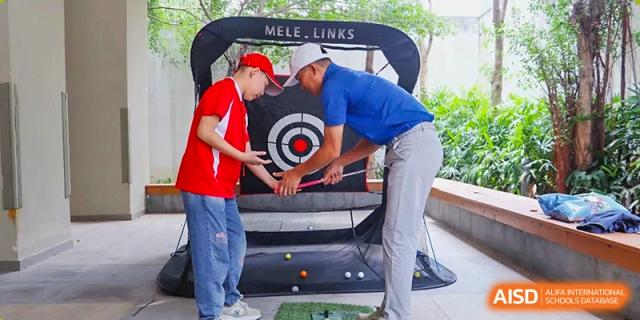 A golf instructor from Sanya Haiya  Foreign Language School helps a student with their swing at a practice net.