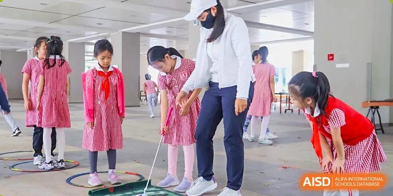 A teacher from Sanya  Haiya  Foreign Language School gives a student a putting lesson on a grassy area.