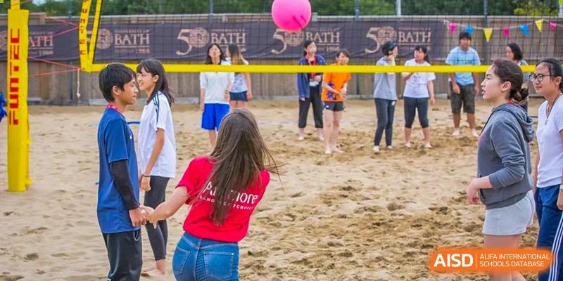Sanya Haiya  Foreign Language School students playing volleyball on a sandy court.