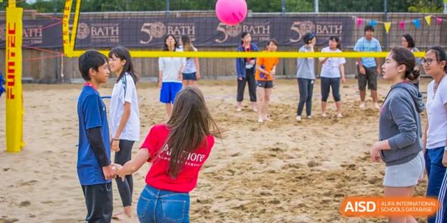 Sanya Haiya  Foreign Language School students playing volleyball on a sandy court.