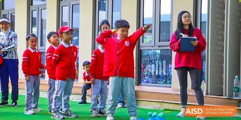 A boy from Sanya Haiya  Foreign Language School in a red jacket striking a pose outdoors.