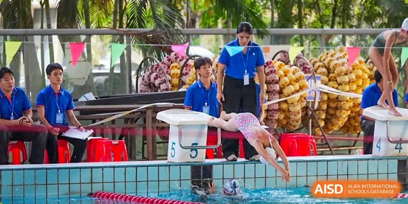 A student from Sanya Haiya  Foreign Language School diving into a pool from a starting block.