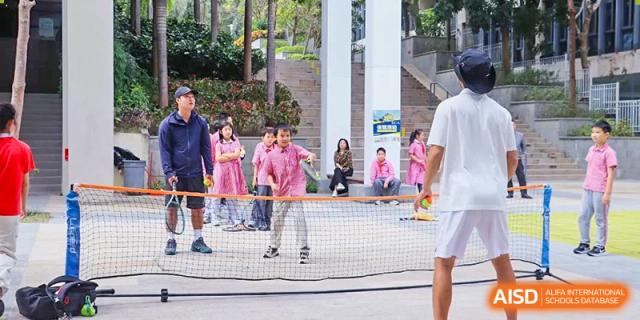 Students from Sanya Haiya  Foreign Language School playing badminton on an outdoor court.