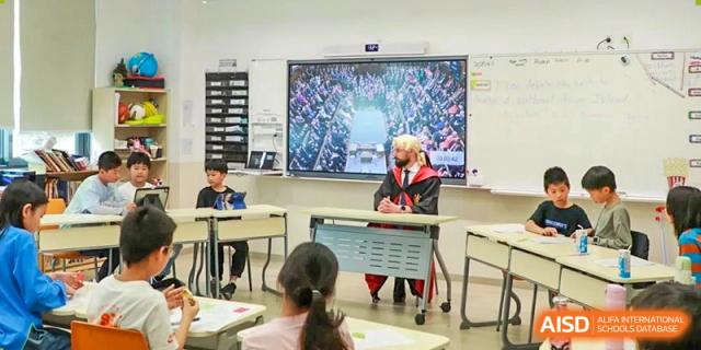 A teacher sitting at a desk and interacting with students in a classroom at Shanghai High School International Division.