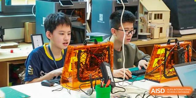 A student concentrating while working with a computer and an orange, transparent machine or device at Shanghai High School International Division.