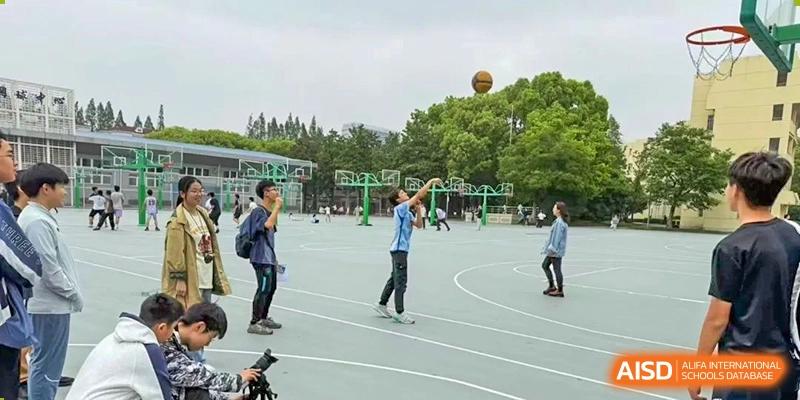 A student taking a basketball shot on an outdoor court at Shanghai High School International Division.