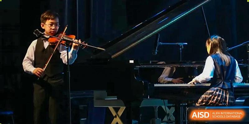 A close-up view of a grand piano being played on a dark stage during a recital at Shanghai High School International Division.