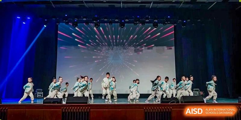 Students performing a dynamic dance routine under stage lighting at Shanghai High School International Division.