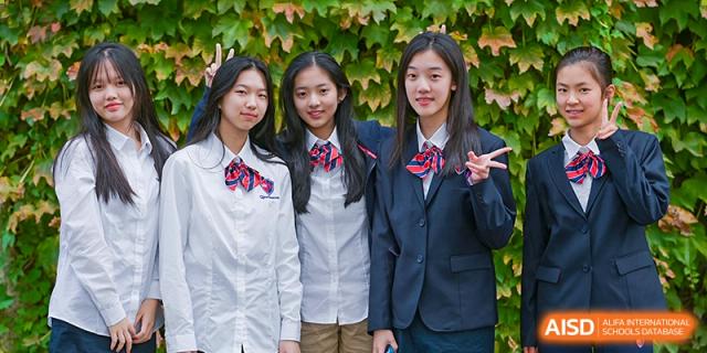 Three female students from Shanghai Qibao Dwight High School pose outdoors in their school uniforms.