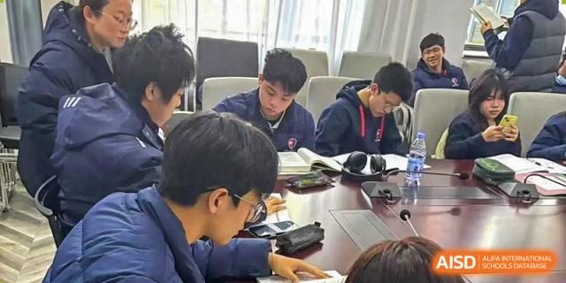 Students from Shanghai Qibao Dwight High School study together, looking at a textbook.