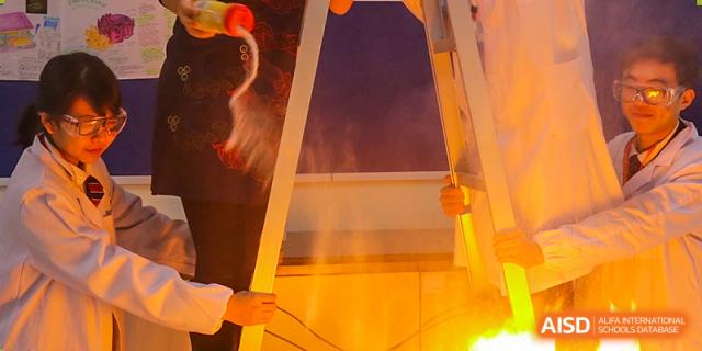 A fire-based science experiment being conducted by students at Shanghai Qibao Dwight High School, showing a bright orange flame.