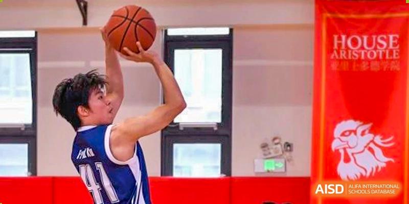 A close-up shot of a basketball player from Shanghai Qibao Dwight High School holding the ball up high, preparing to shoot.