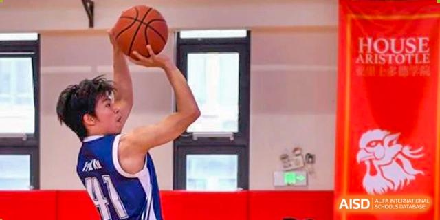 A close-up shot of a basketball player from Shanghai Qibao Dwight High School holding the ball up high, preparing to shoot.