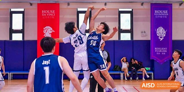 A basketball player from Shanghai Qibao Dwight High School attempts a shot while being defended.