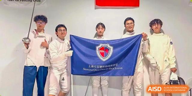 A group of fencing students and coaches from Shanghai Qibao Dwight High School pose with a school banner.