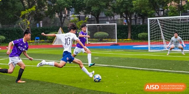 A student from Shanghai Qibao Dwight High School wearing jersey number 10 dribbles a soccer ball during a game.