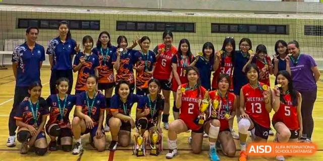 A group of female students from Shanghai Qibao Dwight High School, some holding trophies, pose together.