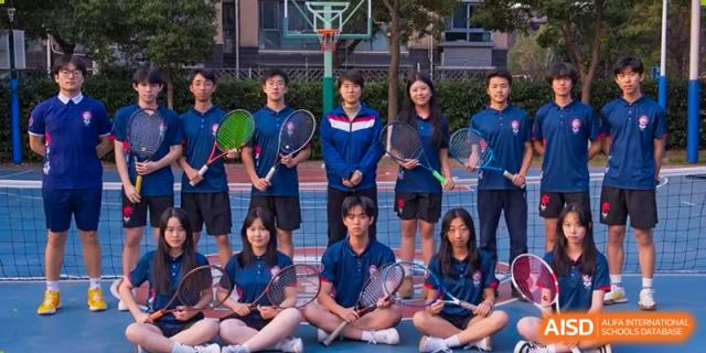 The tennis team from Shanghai Qibao Dwight High School poses together on a court.