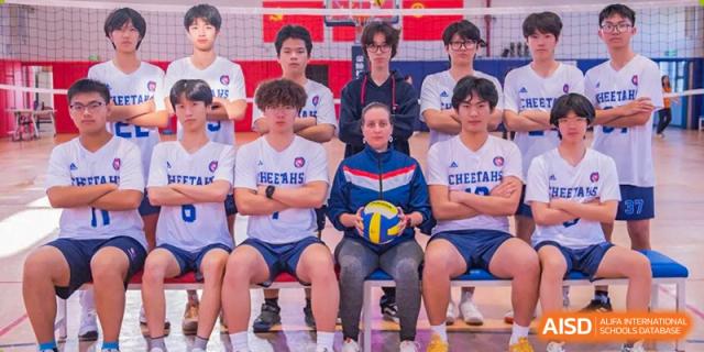 The Shanghai Qibao Dwight High School volleyball team poses for a photo, one player holding a ball.