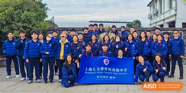 Students and staff from Shanghai Qibao Dwight High School pose with a banner that reads "Shanghai Qibao Dwight High School."