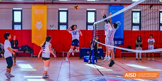 Students from Shanghai Qibao Dwight High School play volleyball in a gym.
