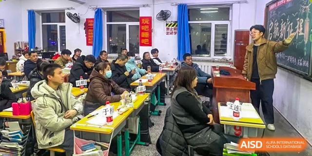Parents or guardians seated at desks during a night meeting or information session at Shenyang Feiyue Experimental School.